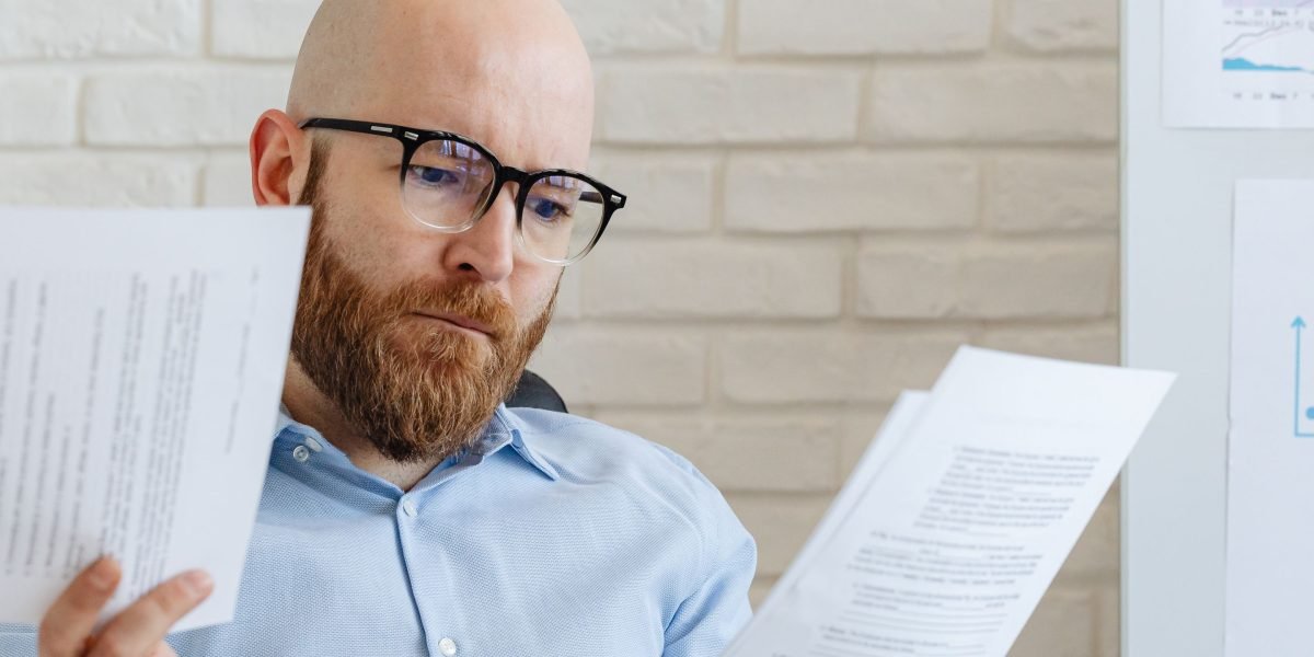 A professional thoughtfully reviews documents, symbolizing the challenges of navigating complex regulatory factors in tech.